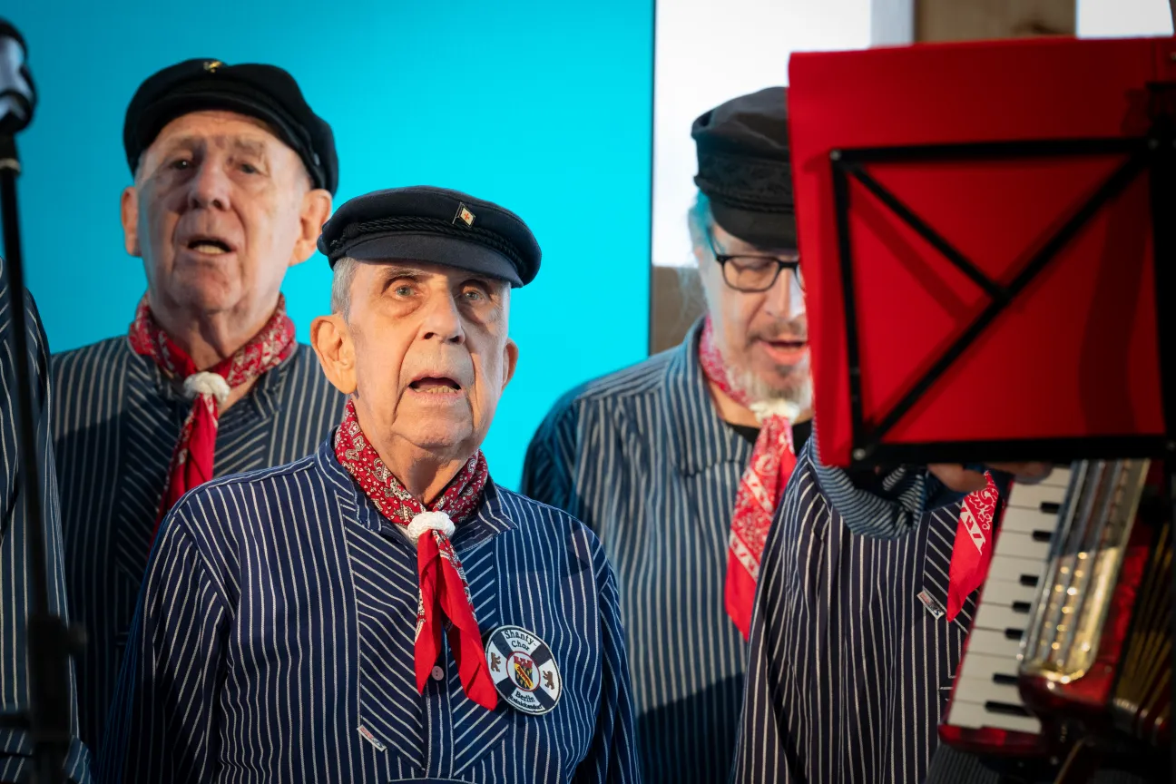 Ältere Herren vom Shantychor tragen ein traditionelles Seemanshemd und singen.