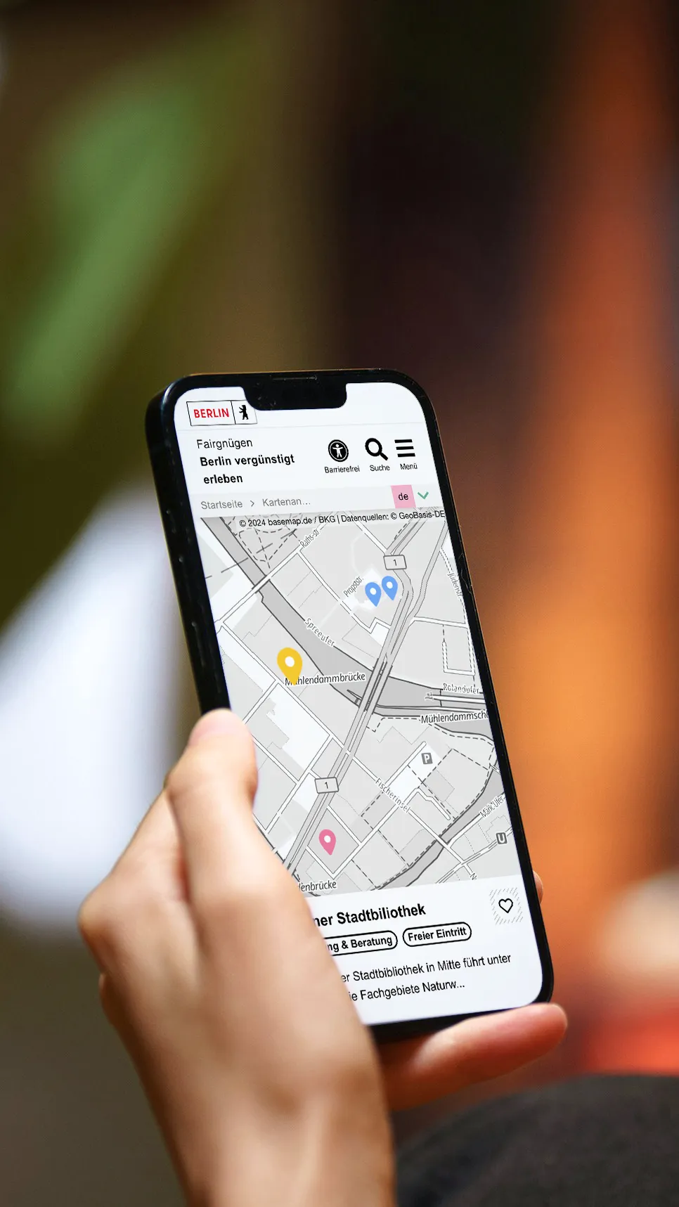 Hand hält Smartphone. Darauf ist eine Straßenkarte zu sehen.