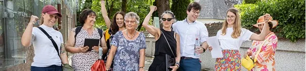 Menschen verschiedenen Alters stehen nebeneinander und freuen sich. Manche halten den Arm in die Höhe. 